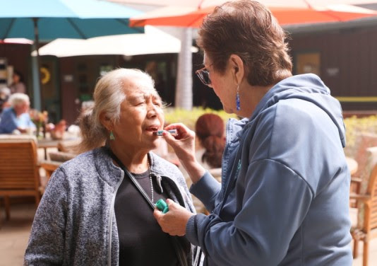 Woman putting lipstick on another woman
