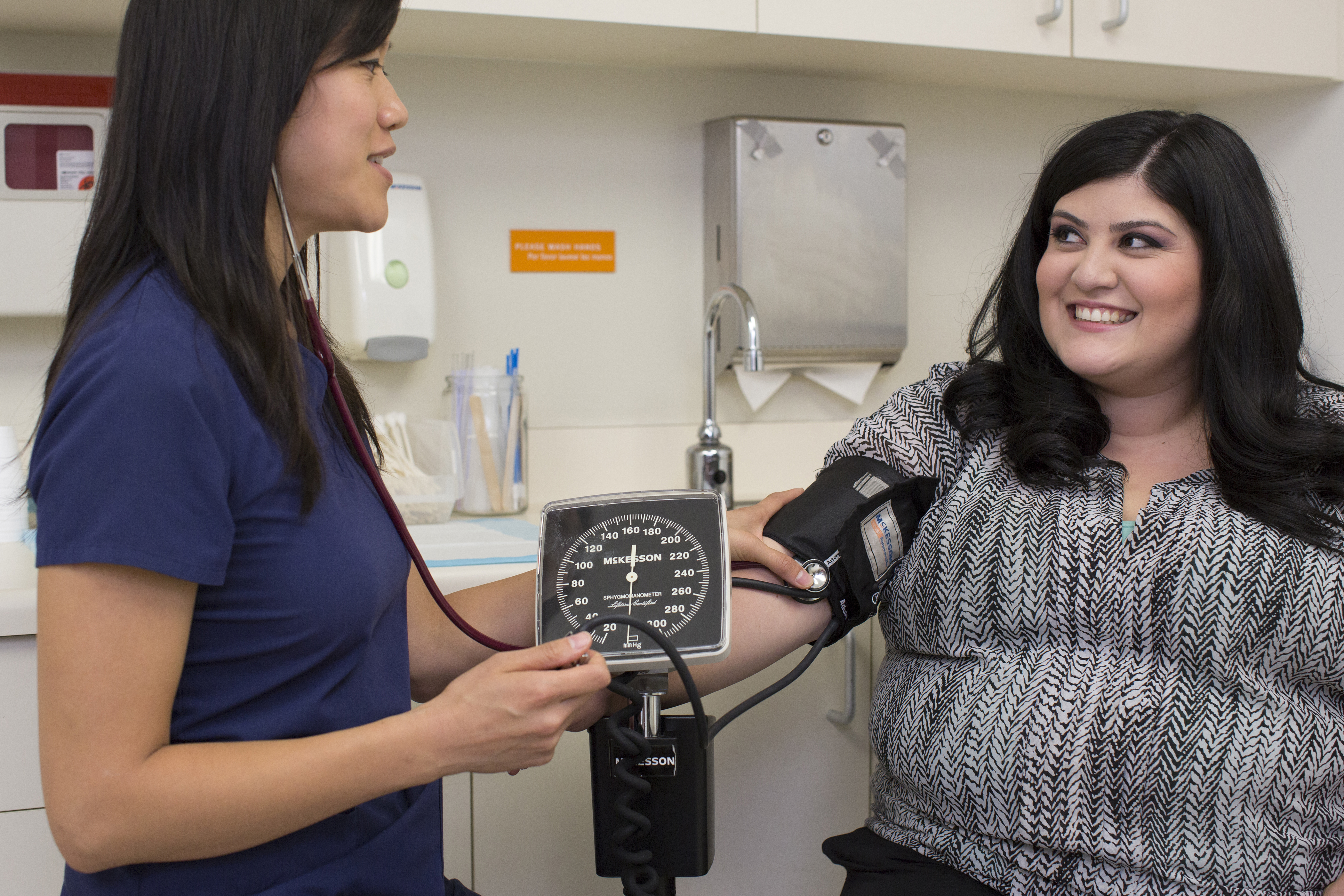 woman in medical scrubs taking blood pressure of female patient