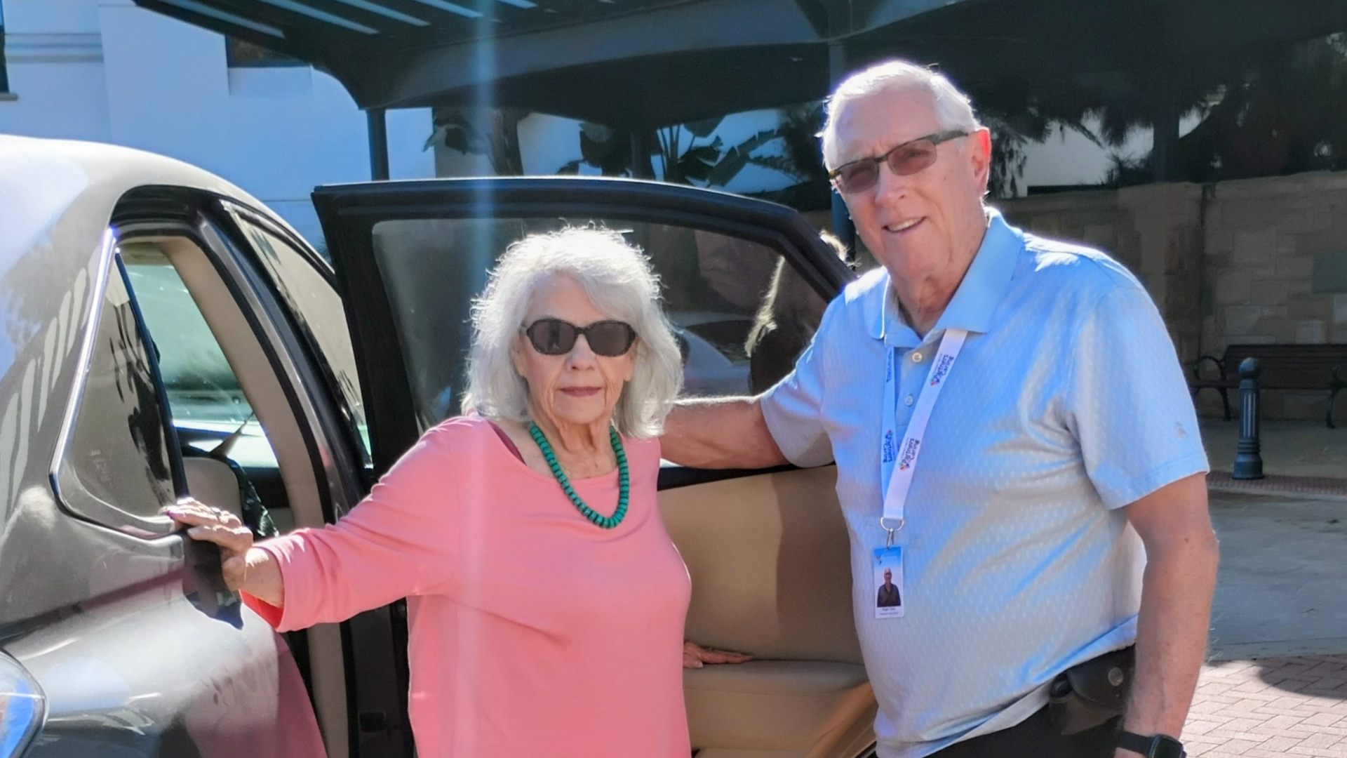 man and woman standing by a car smiling