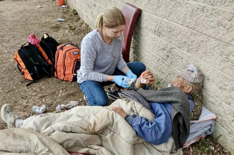 Doctors Without Walls volunteer assists homeless man