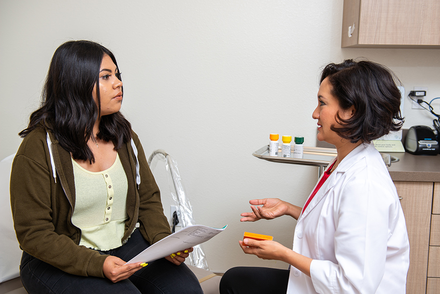 Woman in lab coat talking with female patient