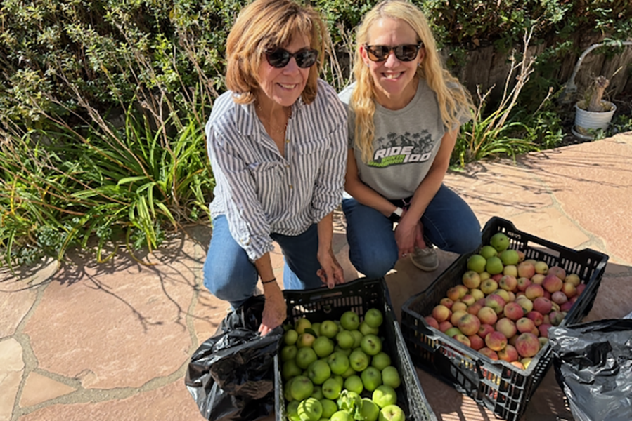 Two women smiling with boxes of fruits and vegetables