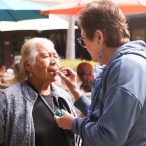 Woman putting lipstick on another woman