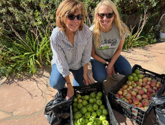 Two women smiling with boxes of fruits and vegetables