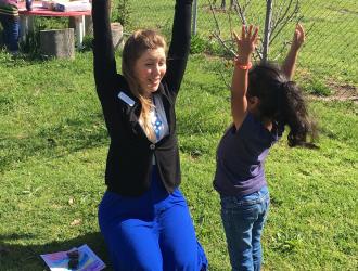 Counselor and girl with arms raised to the sky