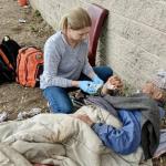 Doctors Without Walls volunteer assists homeless man