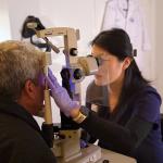 Optometrist using equipment to examine eyes of man