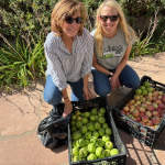 Two women smiling with boxes of fruits and vegetables