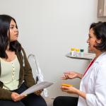 Woman in lab coat talking with female patient