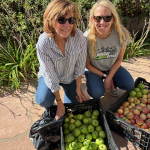 Two women smiling with boxes of fruits and vegetables
